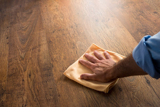 Male hand cleaning hardwood floor with a microfiber cloth.