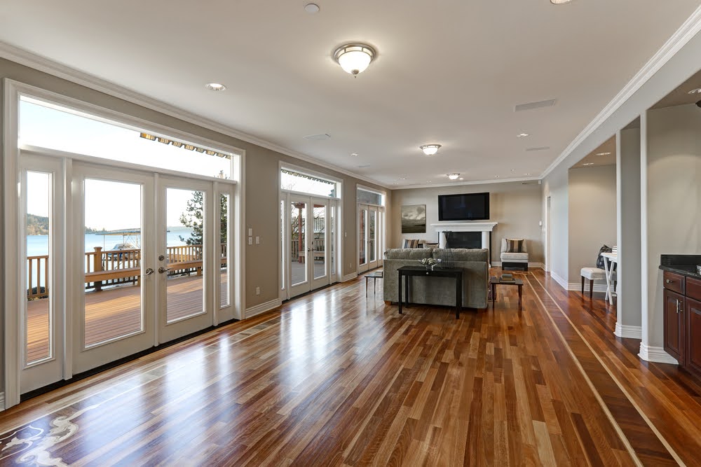 Luxury spacious family room with polished hardwood floor and wall of glass doors.